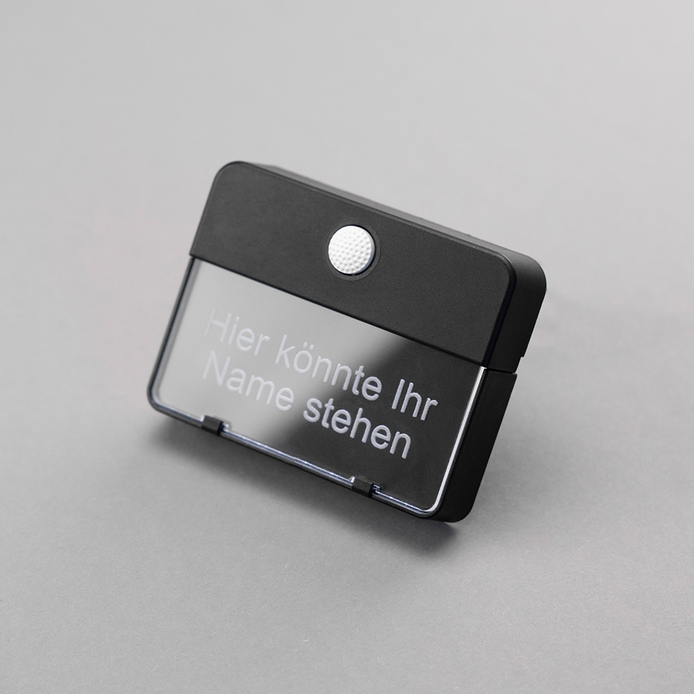 Schwarzer ETA 651-Klingeltaster auf grauem Hintergrund; auf dem Namensschild steht "Hier könnte Ihr Name stehen"