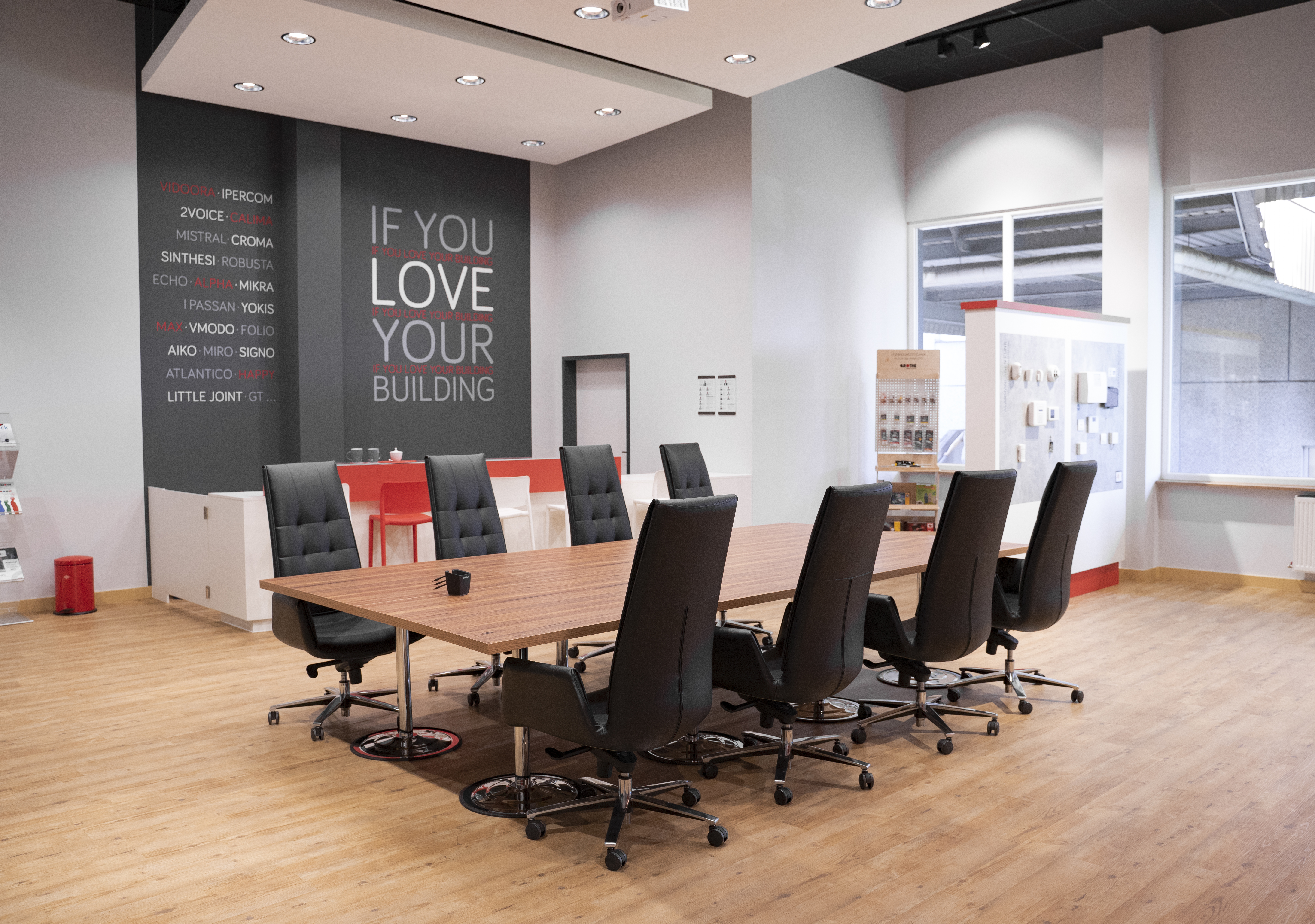 Grothe-Showroom mit großem Tisch in der Mitte und 8 Bürostühlen; an der grauen Wand im Hintergrund ist "If you love your building" zu lesen
