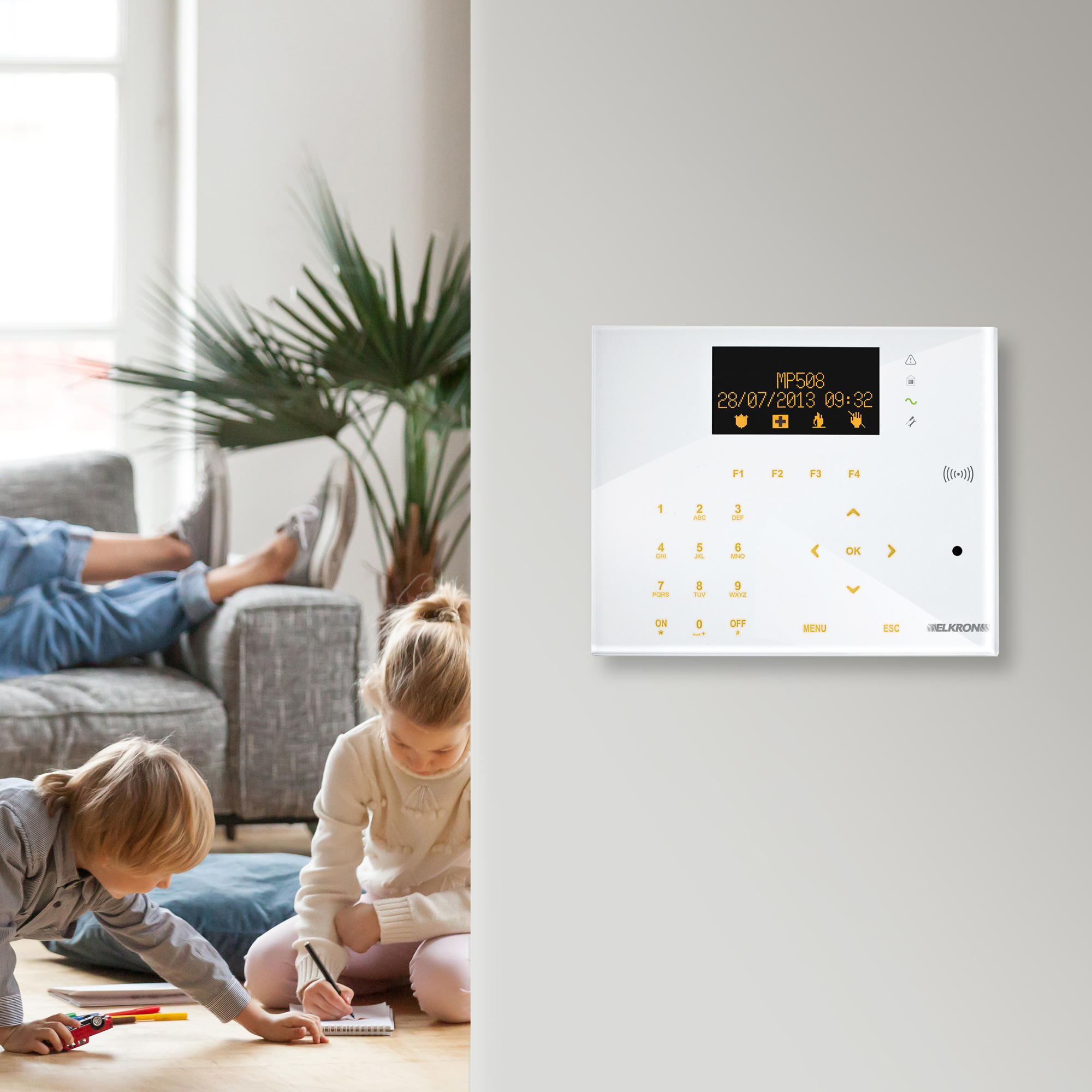 Alarm-Bedienpanel, angebracht an einer Wand; im Hintergrund ist ein Wohnzimmer zu sehen, in welchem Kinder miteinander spielen