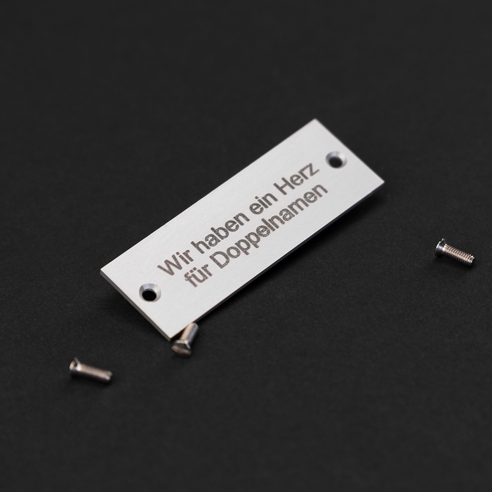 Edelstahl-Gravierschild liegend; darauf steht "Wir haben ein Herz für Doppelnamen"
