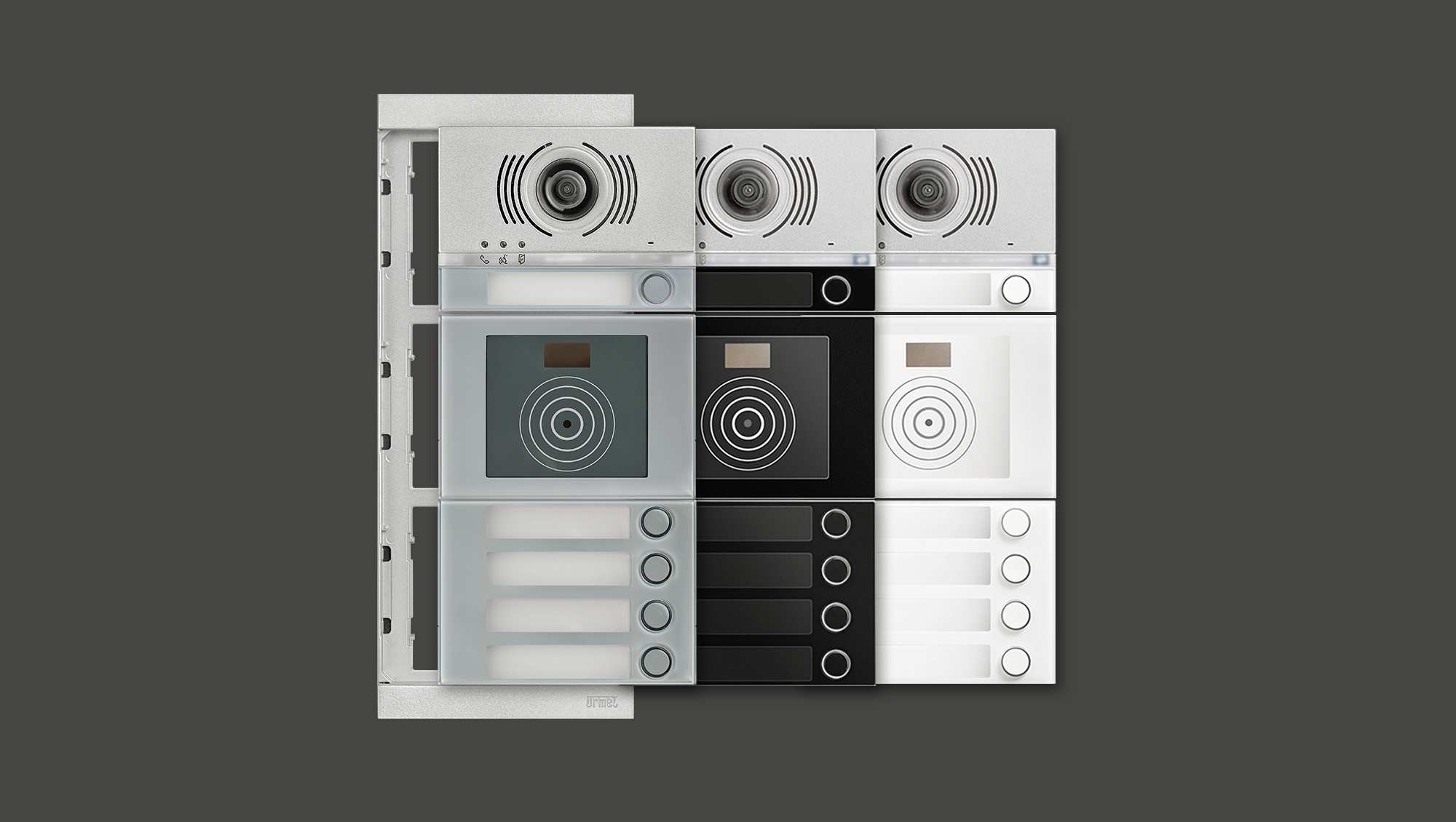 Drei ALPHA Türstationen hintereinander versetzt, in Grau, Schwarz und Weiß; dahinter sieht man den Adapterrahmen