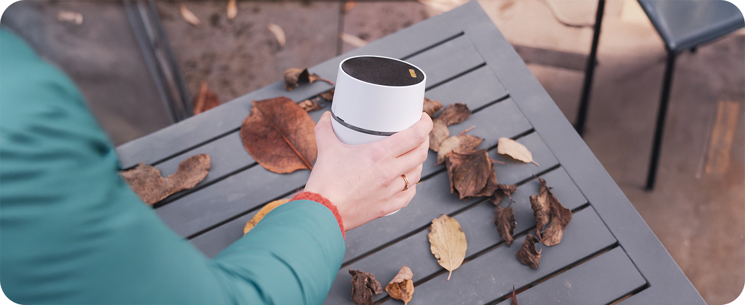 Eine Hand ist im Begriff den Funkgong CALIMA 200 auf einem Gartentisch abzustellen
