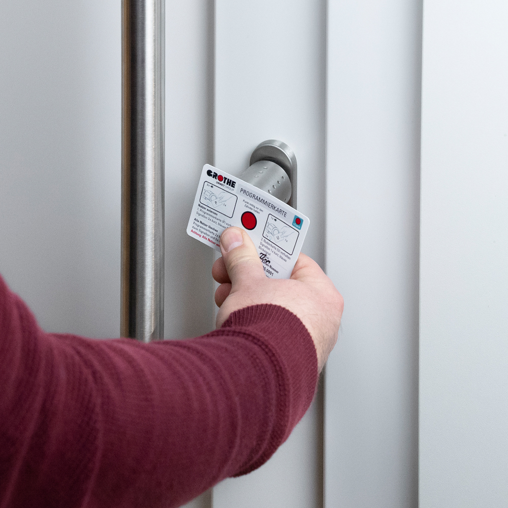 Tür mit eingebautem eLock-Schließzylinder und einer Hand, die einen Näherungskarte davorhält