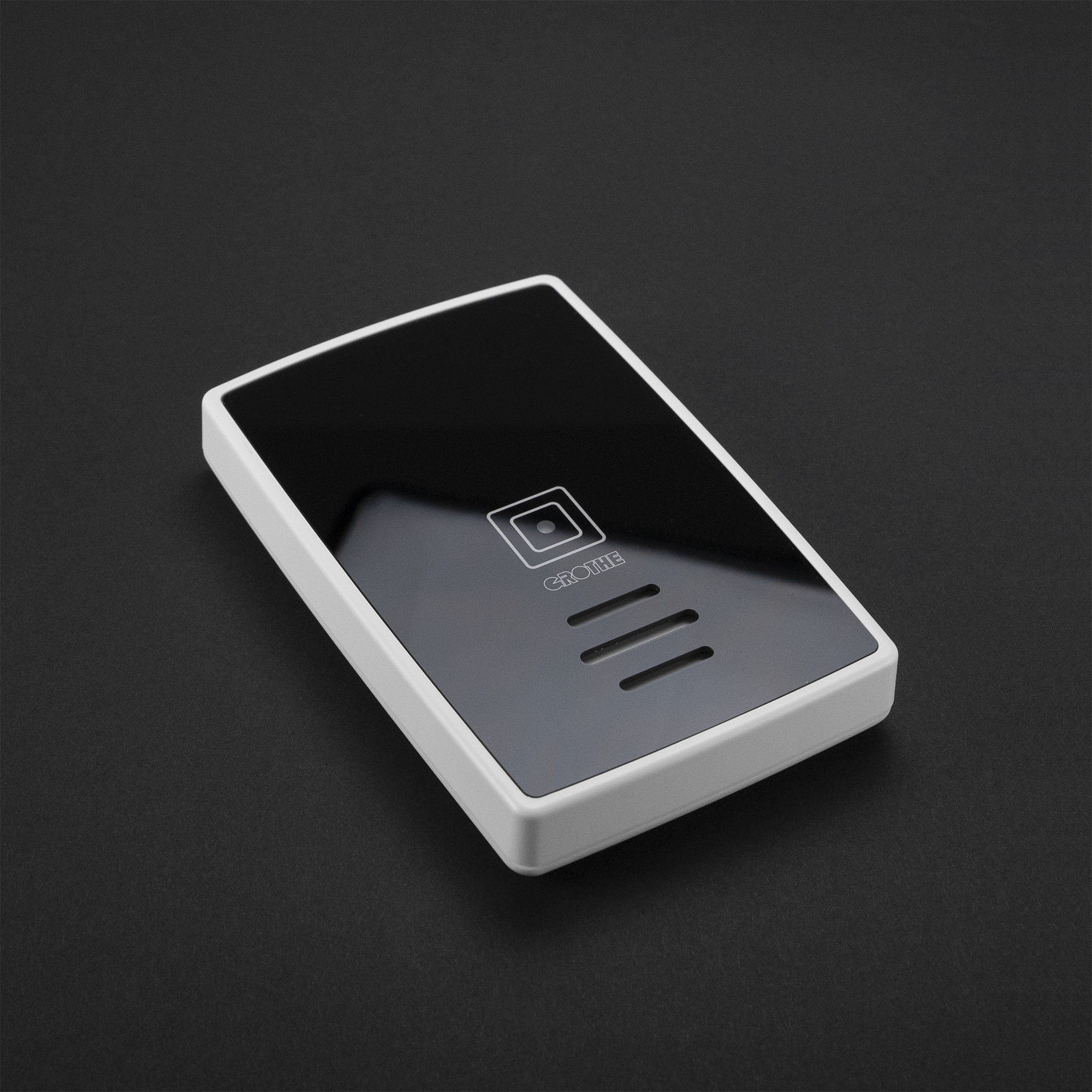 Schwarzer Funkgong mit hochglänzender Oberfläche, drei horizontalen Schlitzen und quadratischem Zierfeld, schräge Draufsicht.