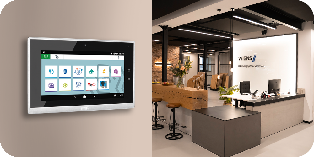 MAX Videomonitor auf Wand mit einer Emfpangstheke im Hintergrund