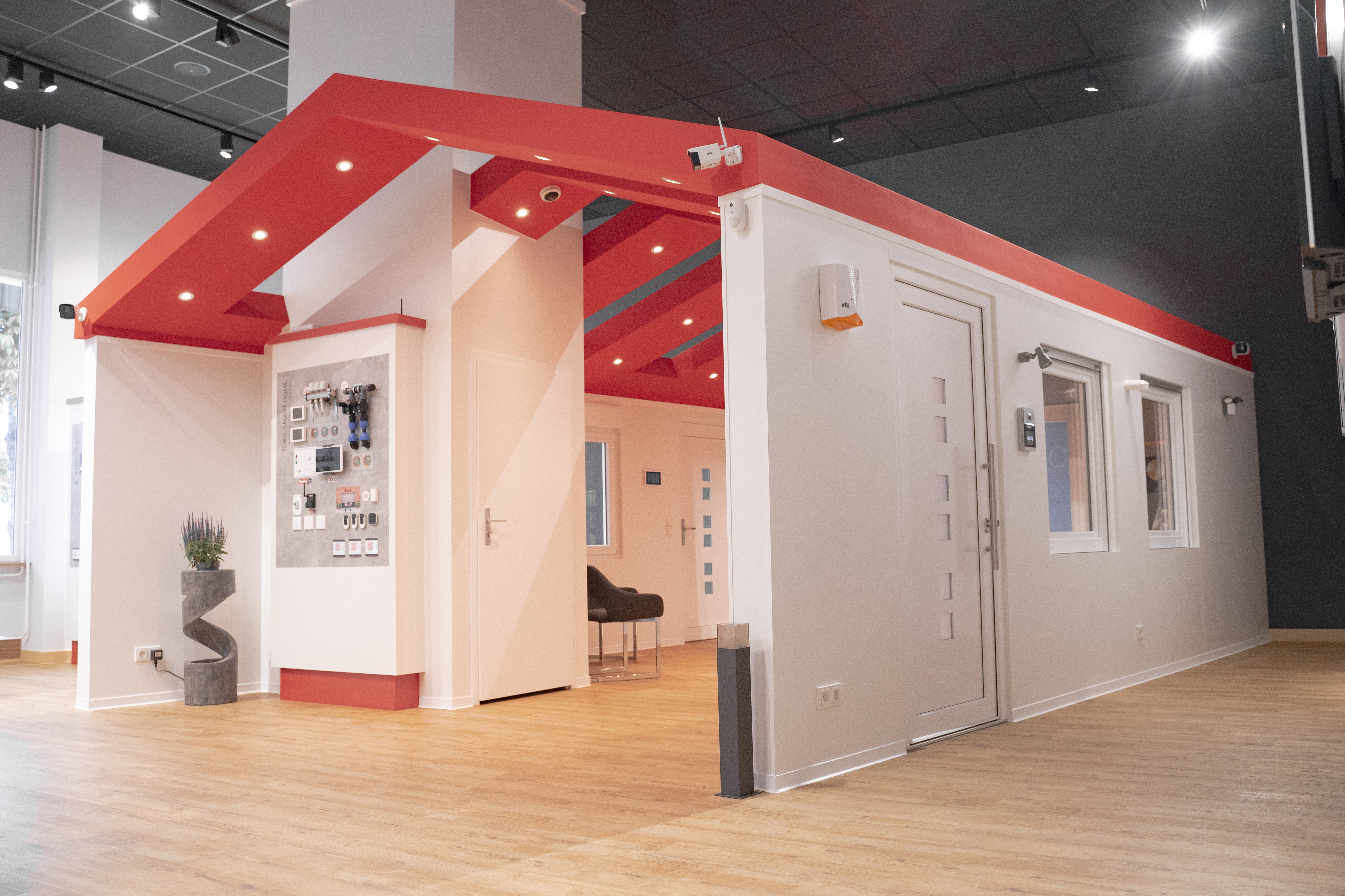 Hausförmiger Messestand im Grothe-Showroom mit weißen Wänden und Türen und einem roten Dach