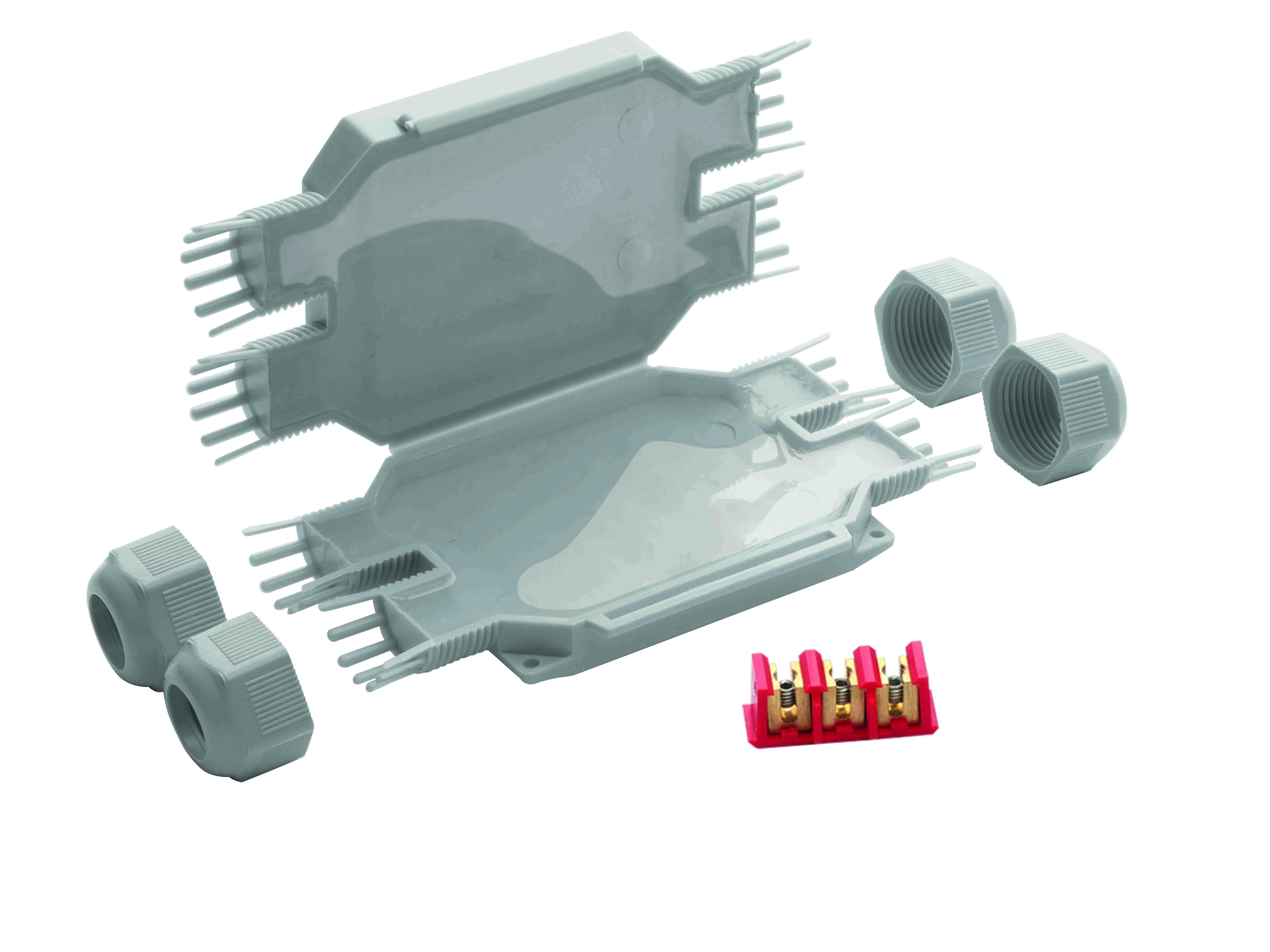 Längliche graue Mikro-Verbindungsmuffe, halb geöffnet, mit Gel gefüllt. Davor liegt eine Schraubklemme.