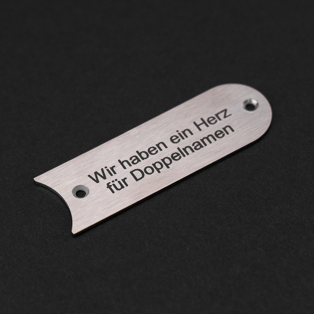 Edelstahl-Gravierschild seitlich liegend; darauf steht "Wir haben ein Herz für Doppelnamen"