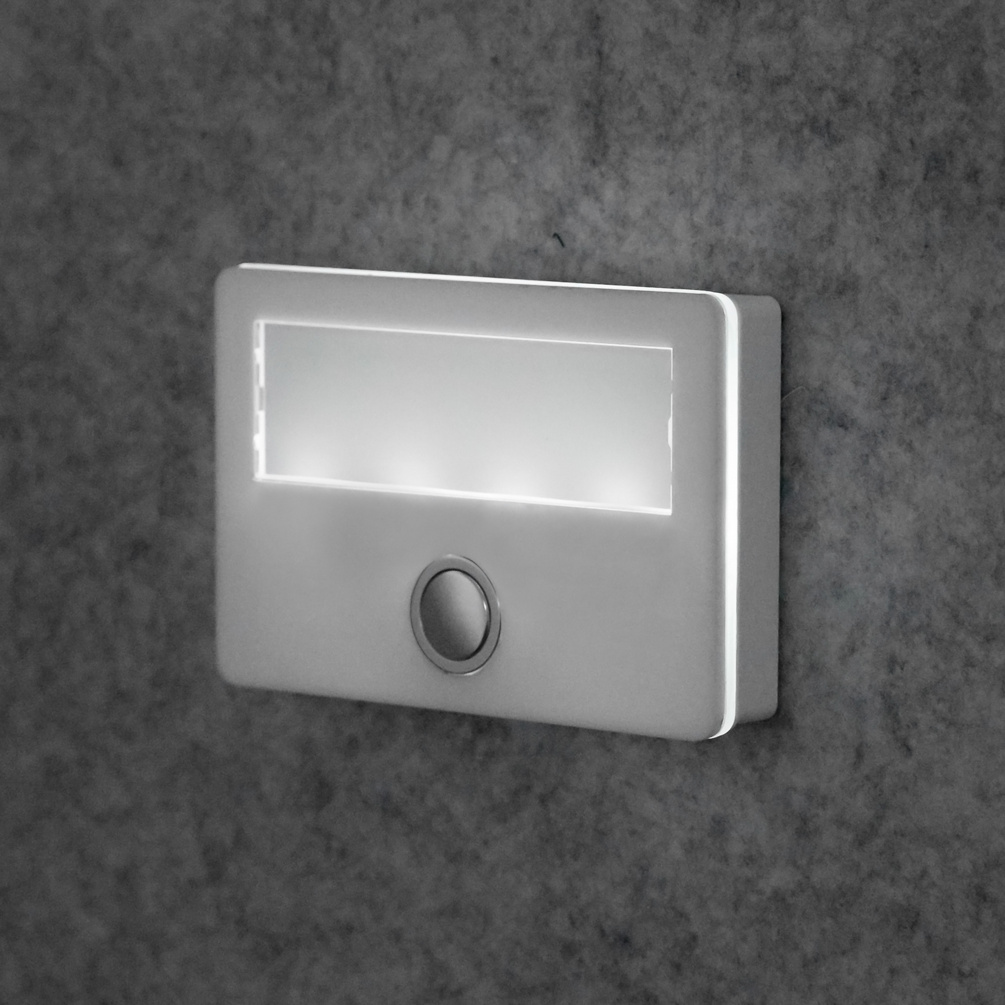 Seitlich beleuchtete Etagenplatte mit rundem Taster und Namensschild, Ansicht von schräg vorne rechts an der Wand.