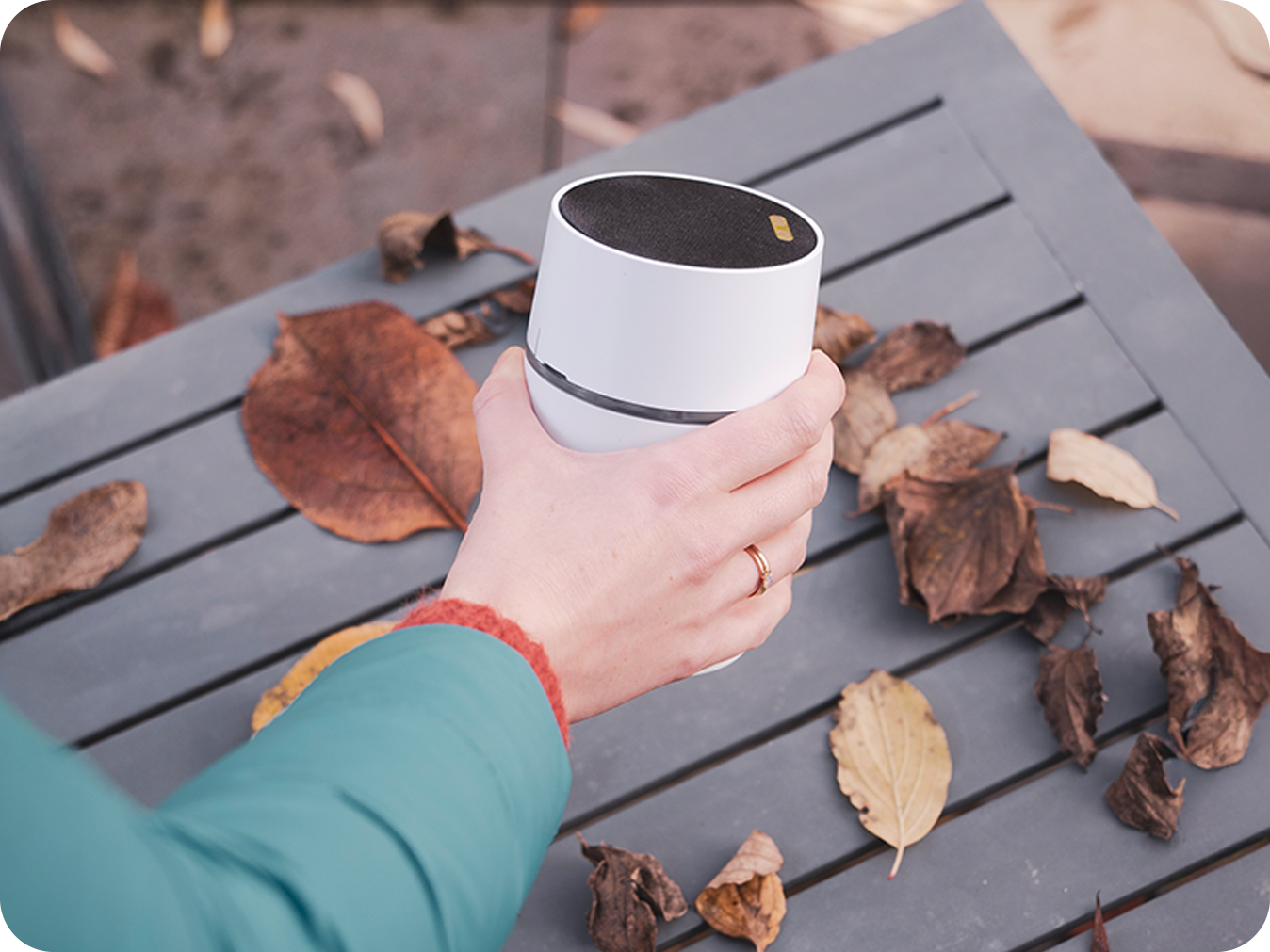 Eine Hand ist im Begriff den Funkgong CALIMA 200 auf einem Gartentisch abzustellen
