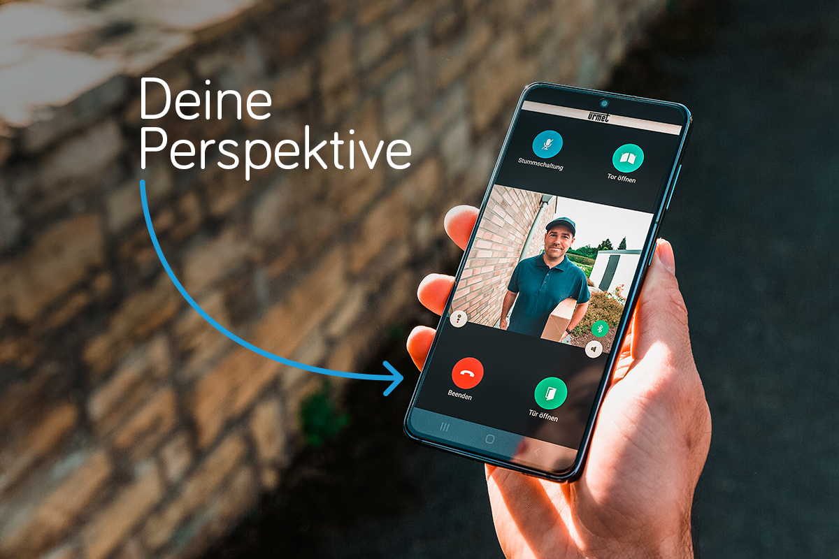 Hand hält Smartphone; auf dem Display ist die App zu erkennen, die einen Paketboten vor der Tür zeigt; daneben steht an einem Pfeil "Deine Perspektive"